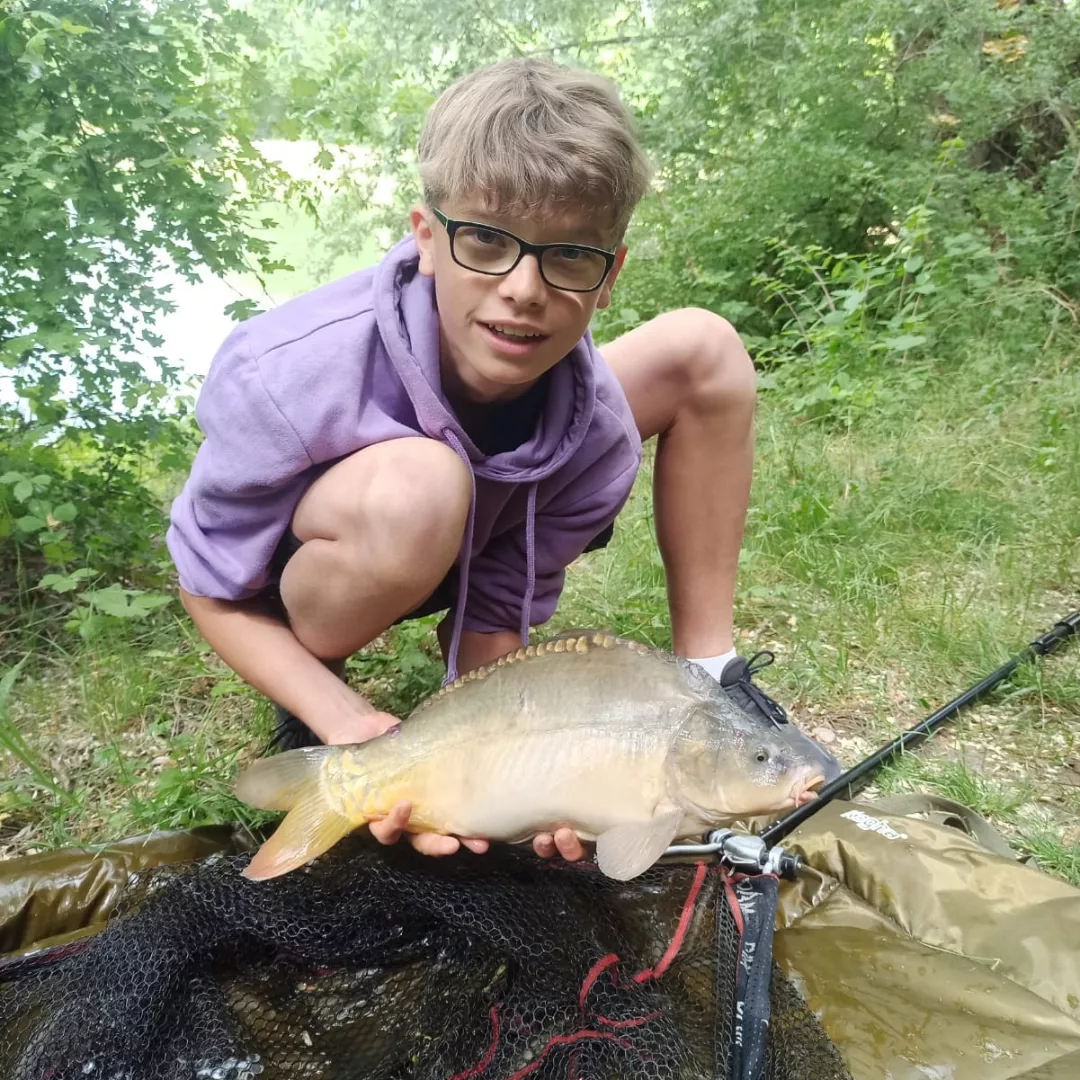 Junger Angler hält seinen gefangenen Fisch